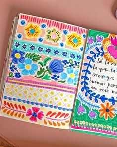 two notebooks with colorful designs on them next to a clock