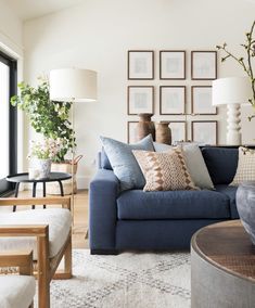 a living room with blue couches and pictures on the wall behind them in frames