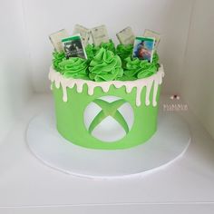 a cake decorated with green icing and photos on top is displayed in a white box