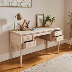 a white desk with two drawers and a lamp on it next to a potted plant