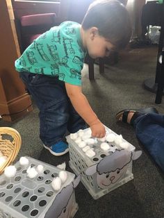 a young boy playing with an egg carton filled with white eggs on the floor