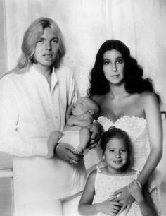 an old black and white photo of two women, one holding a baby while the other holds a doll