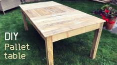 a table made out of pallet wood sitting in the grass next to a potted plant