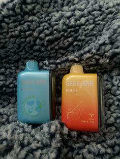 two small lighters sitting on top of a gray blanket next to eachother