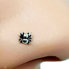 a small black and white spider charm on the side of a woman's stomach