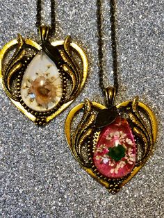 These necklace's pendants measure 1.5" x 1.5".  ⛓ ⛓  Each features a small flower specimen in a resin center. 🌸  Chains measure approximately 10" in length. Variations are described as color chain/flower. Bohemian Flower-shaped Resin Jewelry, Bohemian Flower Shaped Resin Jewelry, Resin Necklace With Pressed Flower Pendant, Resin Necklace With Flower Pendant For Birth Flower, Vintage Flower Necklaces With Pressed Flowers, Resin Necklace With Pressed Flowers In Round Pendant, Resin Flower Jewelry With Flower Charm, Vintage Flower Necklace With Pressed Flowers, Resin Birth Flower Pendant Necklace