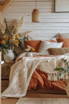 a bed with an orange and white comforter on top of it next to flowers