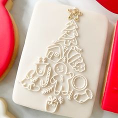 a cookie decorated like a christmas tree on top of a white plate next to cookies