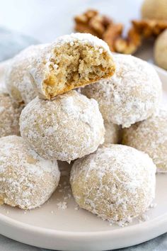 powdered sugar covered donuts in a white bowl on a pink and white table cloth