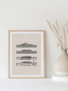 a white vase sitting next to a painting on top of a shelf in front of a wall