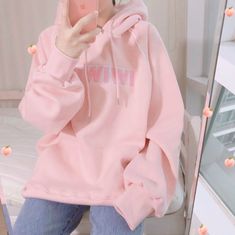 a woman taking a selfie in front of a mirror wearing a pink hoodie