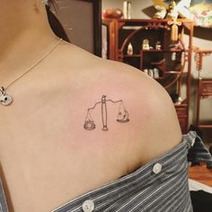 a woman with a tattoo on her shoulder that has a scale and weight scales on it