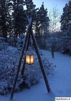 a lantern is lit in the middle of a snow covered area with trees and bushes