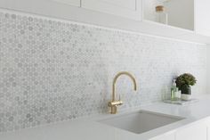 a white kitchen with gold faucet and sink