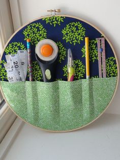 an embroidery project with scissors, pencils, markers and tape on the side of a window sill