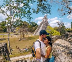 a man and woman standing next to each other in front of a pyramid