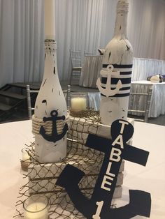 there are two wine bottles and an anchor on top of each other at the table