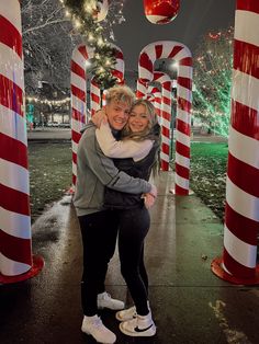 two women hugging each other in front of candy canes