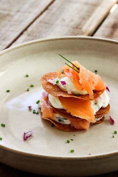 a white plate topped with food and garnish on top of a wooden table