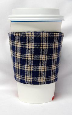 a coffee cup with a blue and white checkered pattern on the sleeve is sitting in front of a white background