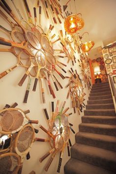 there are many tennis racquets hanging on the wall next to the stairs