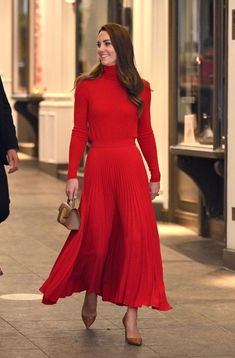 a woman in a red dress is walking down the street