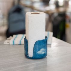 a roll of toilet paper sitting on top of a blue and white cup next to a pair of folded towels