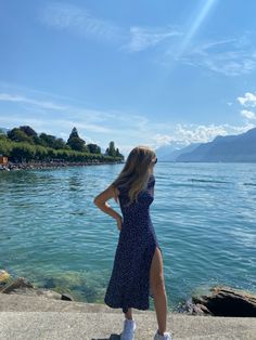 a woman standing on the edge of a lake