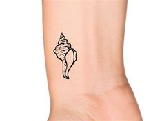 a small tattoo on the ankle of a woman's foot with a sea shell