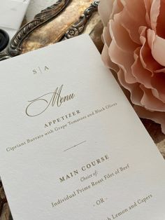 a close up of a menu on a table with a flower in front of it