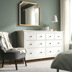 a bedroom scene with focus on the dresser and chair, which has a large mirror over it