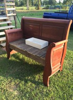 a wooden bench with a white box on it's back sitting in the grass