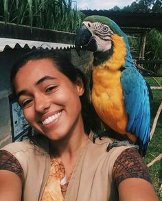 a woman holding a parrot on her shoulder