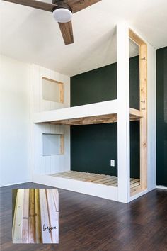 an empty room with two bunk beds and a ceiling fan in the corner next to it