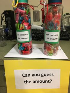 two glass jars with candy in them sitting on top of a counter next to a sign that says can you guess the amount?