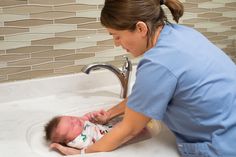 a female nurse is washing a baby in the sink with her hand on it's head