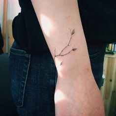 a woman's arm with a small branch tattoo on it