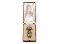 Suspending a large pear-shape peridot, framed by whiplash motifs set with old-mine and rose-cut diamonds, below a diamond ribbon motif, from a rectangular-cut peridot within a navette outline of bezel-set old-cut diamonds, in silver-topped 14k gold. The bottom section is detachable, along with the pin stem. With fitted box from C. Sewell Jeweller. Includes manufacturer's box. Elegant Rectangular Peridot Jewelry, Diamond Ribbon, Gold For Sale, Peridot Pendant, Jewellery Marketing, Whiplash, Silver Tops, Rose Cut Diamond, Bezel Setting