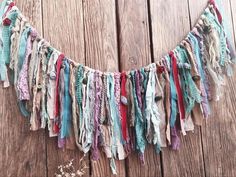 a multicolored scarf is hanging on a wooden wall and it's made out of fabric