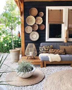 a living room with lots of wicker baskets on the wall and plants in pots