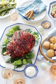 a table topped with plates and bowls filled with meat covered in sauce next to other foods