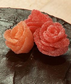 two orange and pink flowers sitting on top of a piece of chocolate covered in sugar