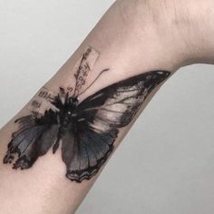 a black and white butterfly tattoo on the wrist