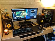 a desk with a keyboard, monitor and speakers