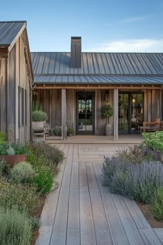 a wooden house with a metal roof and lots of greenery on the front porch