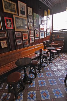 several tables and stools are lined up against the wall in a restaurant with many framed pictures on it