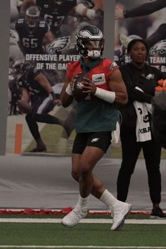 a football player is running with the ball in his hand and two people are watching