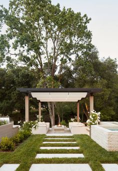 a garden with steps leading up to the pergolated area and trees in the background