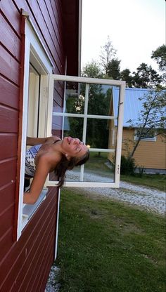 a woman leaning out the window of a red house