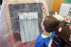 a young boy is drawing on a piece of paper